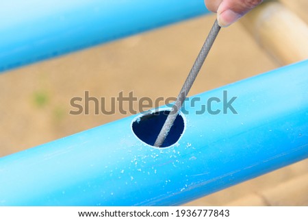 The man use rasp scratch the hole at blue PVC pipe