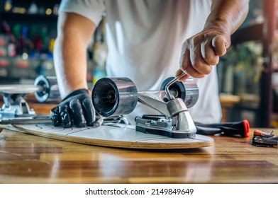 man use the socket tool or hex keys to remove the nuts on skateboard and adjusts suspension in workshop, Skateboard maintenance and repair concept. Selective focus on tool and suspension set - Powered by Shutterstock