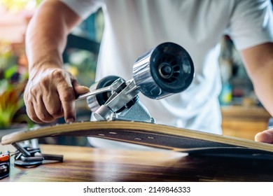 man use the socket tool to remove the nuts on skateboard and adjusts suspension in workshop, Skateboard maintenance and repair concept. Selective focus on suspension set - Powered by Shutterstock