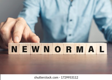 Man use their fingers to touch the word New normal on a wooden block. New lifestyle changes in order to balance, including business, economy, environment and health for Make a big dramatic change.