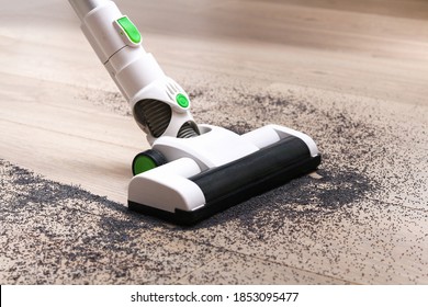 A man uses a bagless vertical cordless vacuum cleaner to clean the floor.