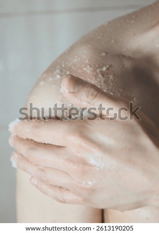 a man uses a body scrub while taking a shower