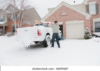 A Man Uses A Broom To Clean Snow Off The Back Of His 4 Wheel Drive Truck After A Winter Storm.