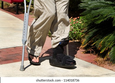 Man Uses Crutches Along With A Foot And Ankle Brace To Help Him Walk After An Accidental Injury.