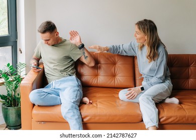A man uses a mobile phone and ignores his wife who wants to talk about problems - Shutterstock ID 2142787627