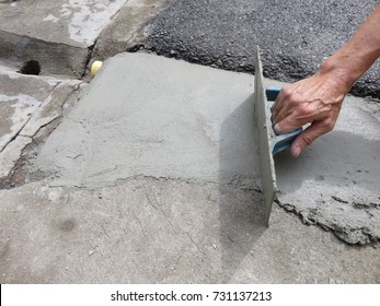 The man uses the plastic trowel to make the smooth surface of concrete (Mixing of Portland cement, sand, and water)