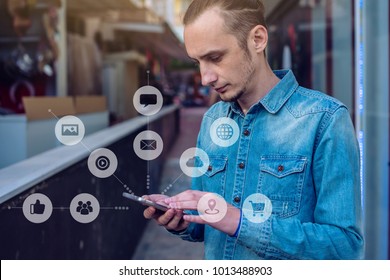 A Man Uses A Smartphone To Access Social Digital Media In The Internet: Shopping, Entertainment, Search And File Storage. The Concept Of A Global Network Expansion