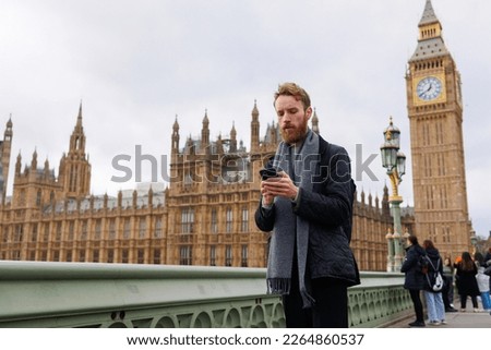 Man uses a smartphone while standing on Westminster Bridge in London, Big Ben in the background