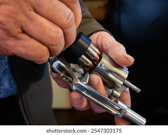 A man uses a speed loader to quickly reload bullets in a revolver.