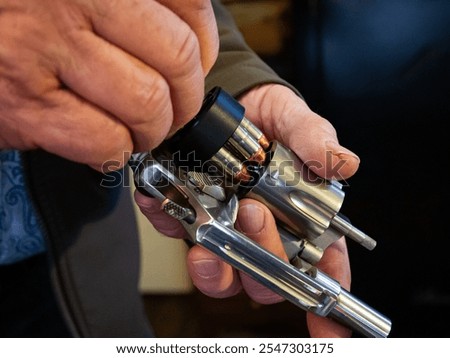A man uses a speed loader to quickly reload bullets in a revolver.