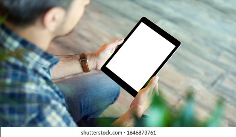 Man uses tablet computer with isolated screen, holding it in his hands. View from above. Clipping path.