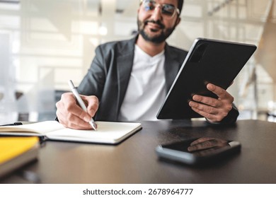 Man uses tablet and notebook for notes at work in office