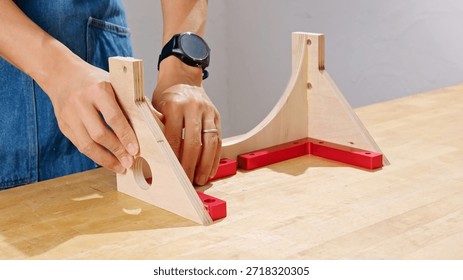 Man using a 90-degree angle corner clamping jig to assemble a woodworking project with glue