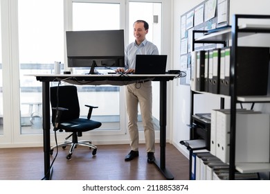 Man Using Adjustable Height Standing Desk In Office For Good Posture