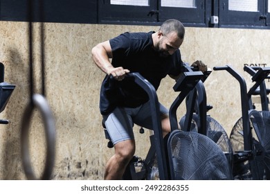 Man using air bike for cardio workout at cross training gym. - Powered by Shutterstock