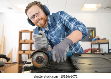 Man Using Angle Grinder On Car Bodywork