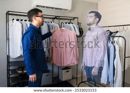 Man is using augmented reality technology to visualize himself wearing a shirt he is holding in his hands