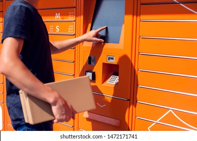 Man Using Automated Self Service Post Terminal Machine Or Locker To Deposit The Parcel For Storage