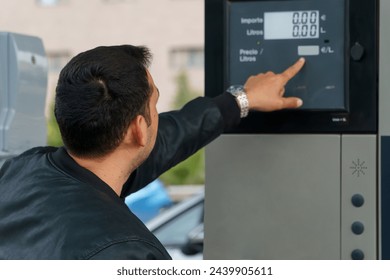 Man using an automatic teller machine to check the amount of fuel	