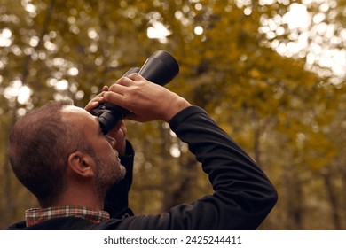 Man using binoculars for birdwatching and other observing animals in nature.