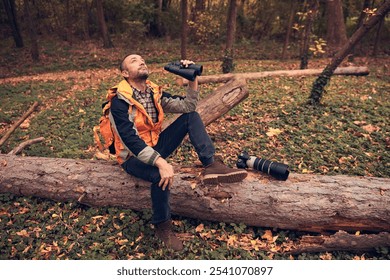 Man using binoculars and camera for bird and animal watching in nature.