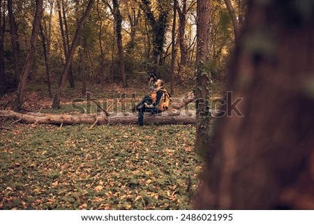 Man using binoculars and camera for bird and animal watching in nature.