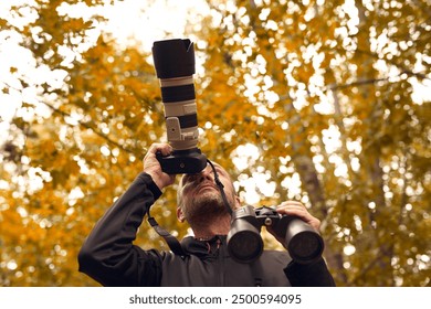 Man using binoculars and camera for birdwatching and other observing animals in nature.