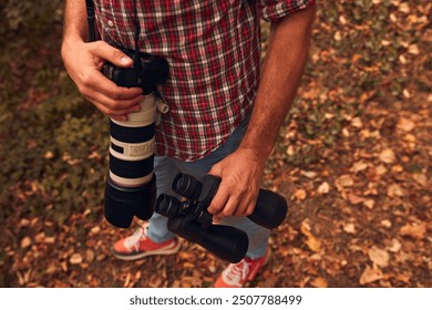 Man using binoculars and camera for birdwatching and other observing animals in nature.