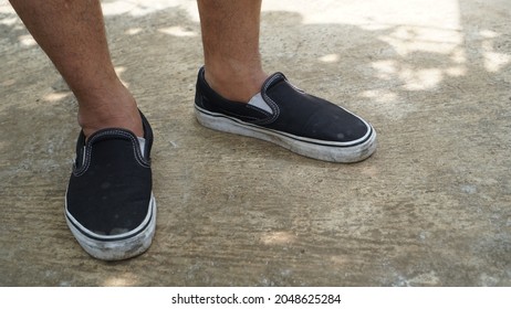 A Man Using Black Slipper Shoes, He Take Shelter Under A Tree. 