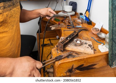 Man using a blowtorch with fire to create a piece of jewellery in a jewellery craft workshop - Powered by Shutterstock