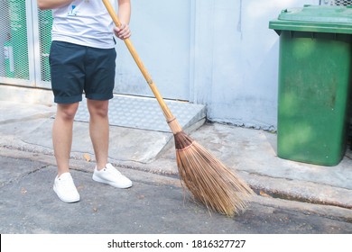 Man Using Broom Sweep The Street Or Floor Garbage Cleaning Service Concept City.Maintenance Worker In Park Garden Cleans The Roads With Broom .Copy Space