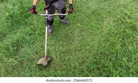 Man using brush cutter for cutting grass.