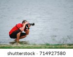 A man is using a camera, taking a picture of nature in a reservoir.
Male photographers wearing red robes are recording wildlife.