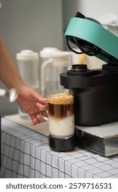 Man using capsule coffee machine with espresso cup. Nespresso is worldwide leader company with coffe machines and capsules.