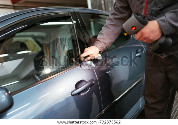 Man\
using car color meter to check color shade of car.\
