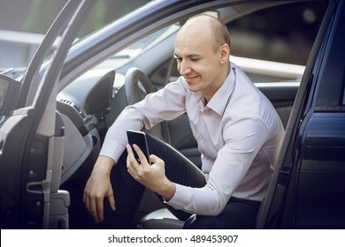 Man Using Cell Phone In Car Door Open