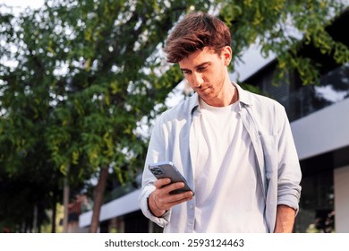 man using cell phone while walking down the street