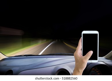Man using cell phone while driving, blur image of the dark road as background.
