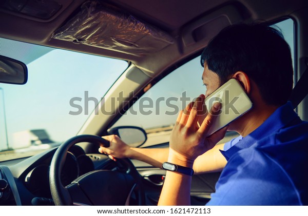 Man using cell phone while driving concept for danger\
of text message and being distracted , using smart phone mobile\
phone in car
