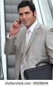 Man using a cellphone at the  bottom of an escalator