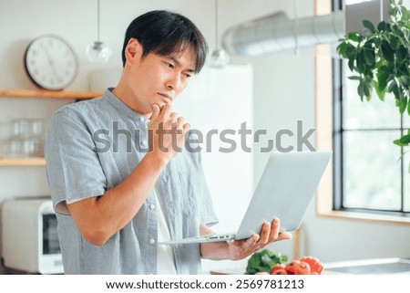 A man using a computer in front of the kitchen (troubled)