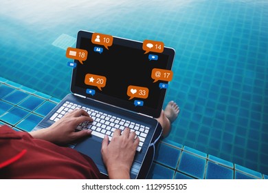 a man using computer laptop at poolside in summer holiday, with social media, social network notification icons