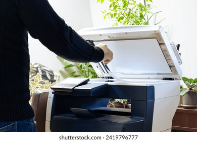A man is using a copier. A man scans or copies documents on a copy machine. Working with a scanner in the office