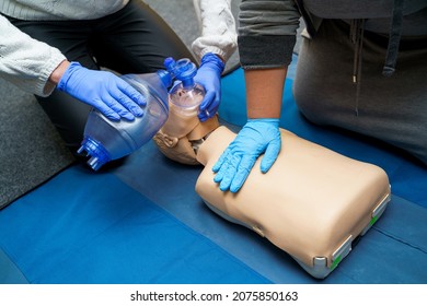 Man using CPR technique on dummy in first aid class. Oxygen mask on medical doll. Stock photo