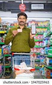 Man Using Credit Card And Mobile Phone At Grocery Store