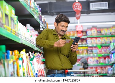 Man Using Credit Card And Mobile Phone At Grocery Store