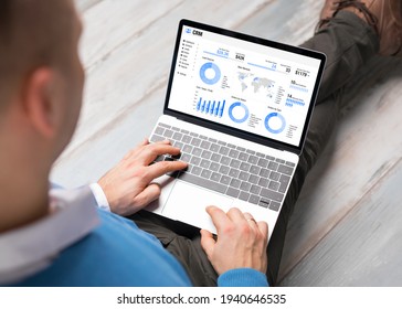 Man using CRM software on laptop with different graphs and charts showing sales data for his business