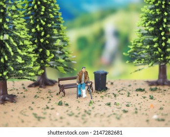 Man using crutches. Miniature figure on the table with unfocus tree. Background is blurred.