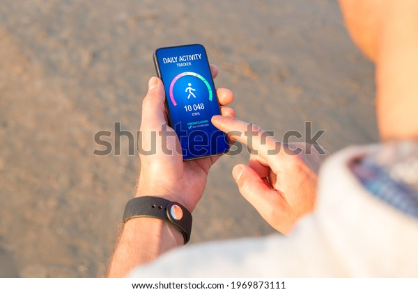 Man using daily activity\
tracking app on mobile phone showing 10 000 steps daily goal\
achievement