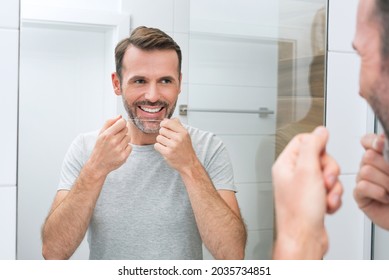 Man Using Dental Floss In The Bathroom. White Teeth And A Beautiful Smile, Morning Hygiene Concept